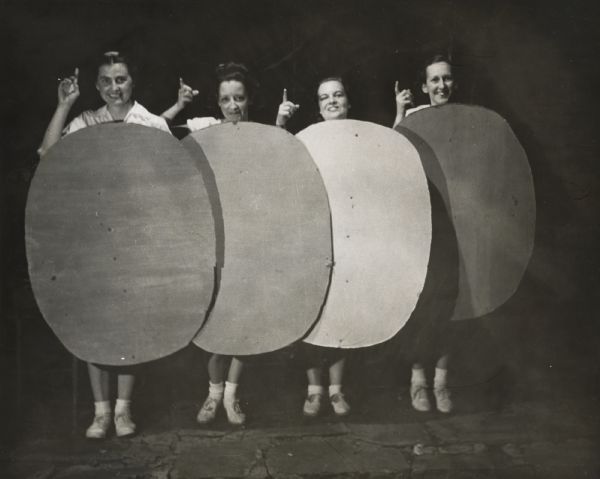 Four women holding up cardboard ovals and pointing, as part of a theatrical performance at Highlander Folk School.