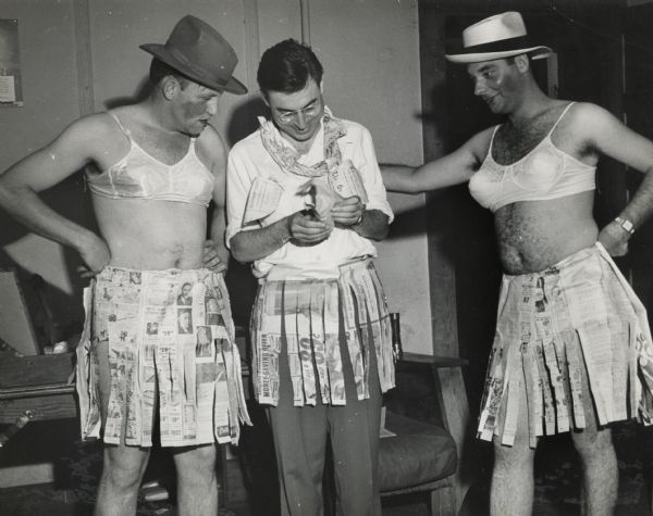 Three men are dressed as women, wearing brasseries, and skirts made from newspaper. Part of a hosiery workers workshop skit at Highlander Folk School.