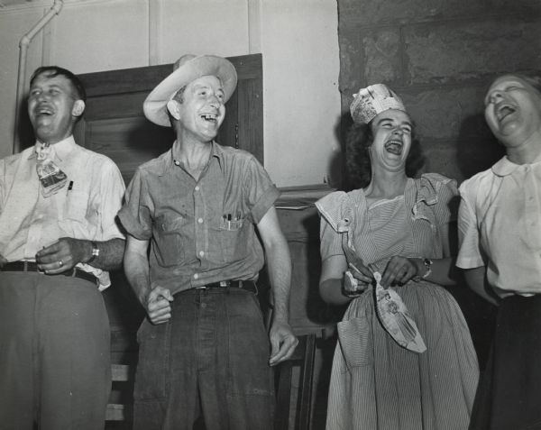 A group of four hosiery workers participating in a skit and wearing accessories made from newspaper, as part of a Highlander Folk School workshop. Joie Willimetz second from right.