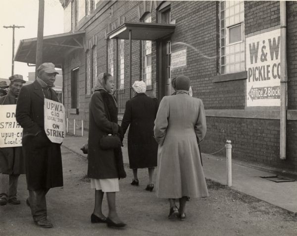 Striking packinghouse workers on a picket line at an unidentified locality.  Sign on side of building reads, "W & W Pickle Co."