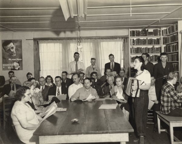 Zilphia Horton playing the accordion and leading a sing-a-long during a Farmers Union session at Highlander Folk School. Myles Horton middle at table; DeJarnette at his right; Mother of Myles Horton further right; Tom Ludwig behind Zilphia in back.