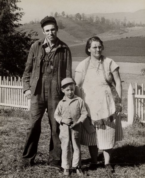 Portrait of an unidentified farm family in a fenced yard.