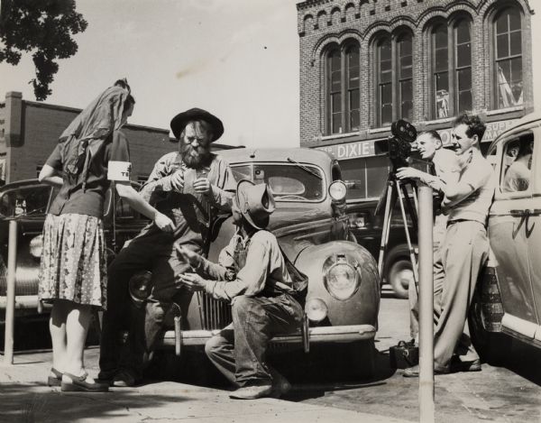 Filming a scene with an 8mm movie camera on a street, in front of a car for the Highlander Film Center.