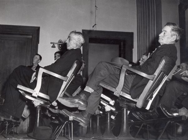 Old men reclining in classroom style chairs.