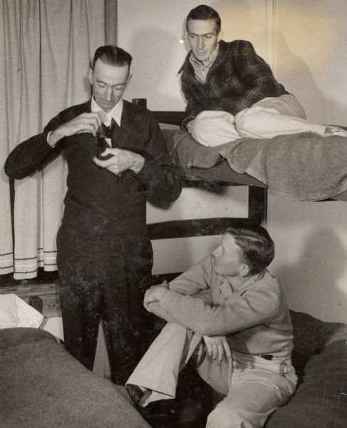 Three men talking around a bunk bed.