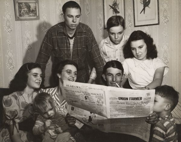 A family reading the newspaper "Union Farmer" together.