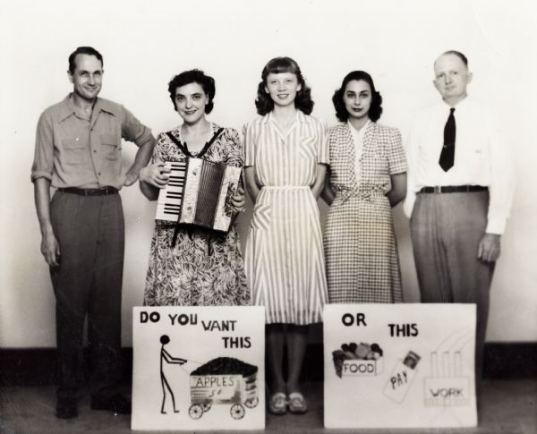 Highlander Chautauqua route traveling group that went to North Carolina and other places during the `40's.  Myles and Zilphia Horton, far left.  Posters read, "Do You Want This (Apples)" and "Or This (Food, Pay, Work)".