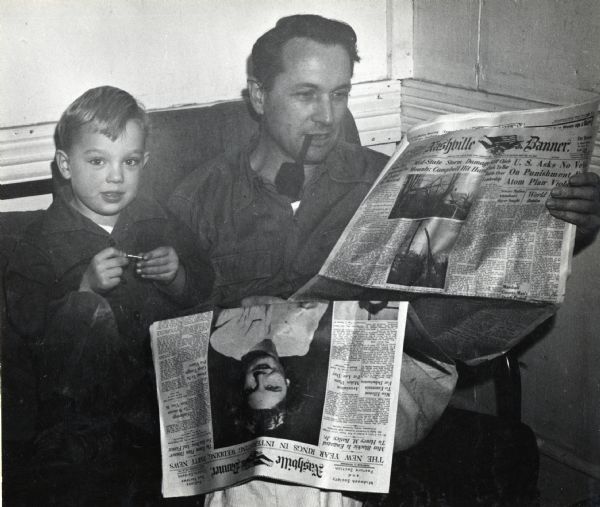 Myles Horton, cofounder of Highlander Folk School, smoking a pipe and reading the Nashville Banner newspaper, posing with his son, Thorsten.