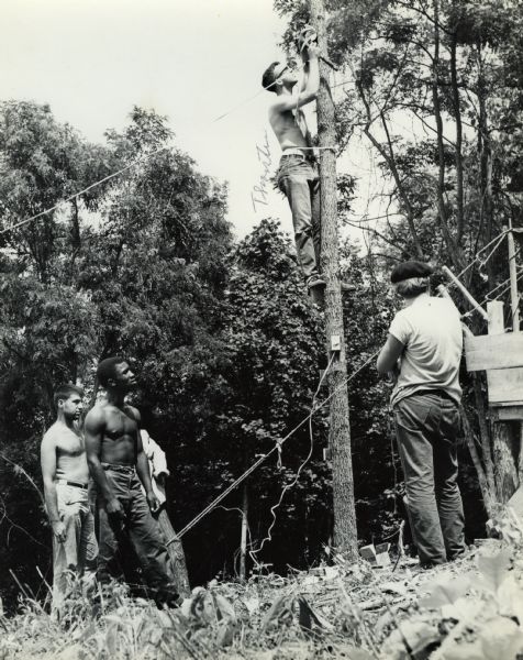 A group of young men, including Thorsten Horton, working on fastening cords to a pole, as part of the North South Smokey Mountain Work Camp.
