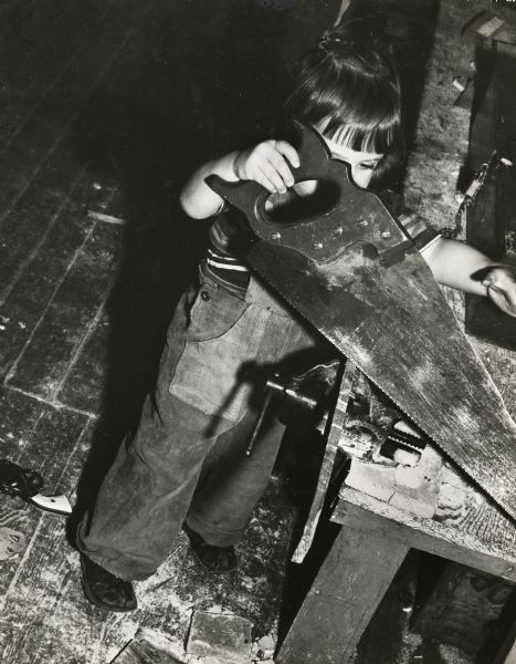 Charis Horton, daughter of Zilphia and Myles Horton, using a large saw to cut wood at Highlander Folk School.