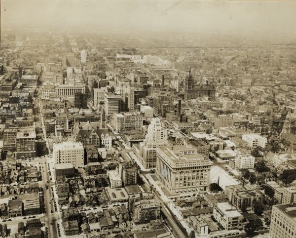 Aerial view of downtown area including churches, homes, and large buildings, stretching to the horizon.