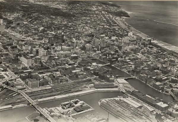 Aerial view of rivers, with Lake Michigan in upper right, train yards, and highway in lower left.