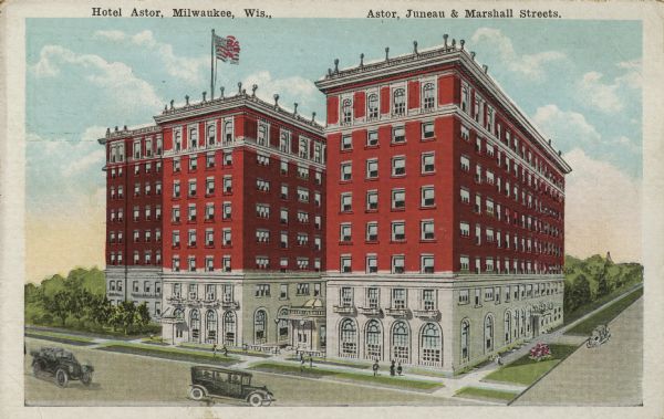 Elevated view of the Hotel Astor at Astor, Juneau & Marshall Streets.  The hotel is a large, red brick building and an American Flag on the roof. There are pedestrians, three cars and trees along the streets. Captions read: "Hotel Astor, Milwaukee, Wis." and "Astor, Juneau & Marshall Streets."