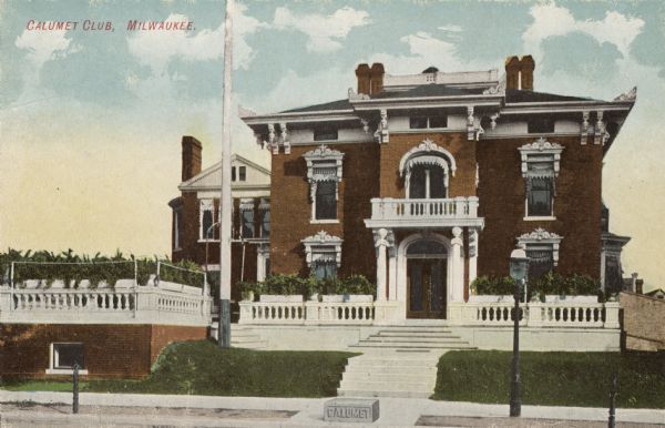 View across street towards a red brick building with a flag pole in the yard on the left. A small stone block that reads "Calumet" is on the sidewalk. Caption reads: "Calumet Club, Milwaukee."