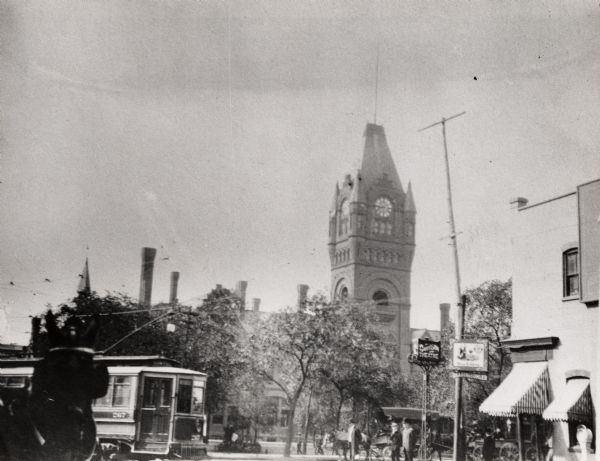 View of depot from the street.  Taken about a block from the building, the image has a trolley, pedestrians, carriages, and signs for the Davison Theatre and the Blue Ribbon Dearing & Omler.