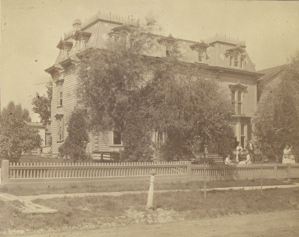 Located at 321 Hanover Street, this house was occupied by George H. Paul as a homestead from 1866 to 1893.  The house has an old fashioned hardwood frame, hewed and sawed hand.  It was part of the old Childs homestead near the corner of Pierce and Hanover Streets.  It was bought by Geo. H. Paul and removed to the west side of Hanover between Pierce and Nattan, and rebuilt.  House is three stories, with a picket fence along the road.  Several people are in front of the house, consisting of one man and a woman standing, three females sitting, and two walking.