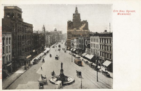 Elevated view from the top of a building looking onto the square and down East Water Street. A fountain with a monument to Henry Bergh is in the lower center of the road. Horse-drawn carriages and two trolleys are on the streets. Caption reads: "City Hall Square, Milwaukee."