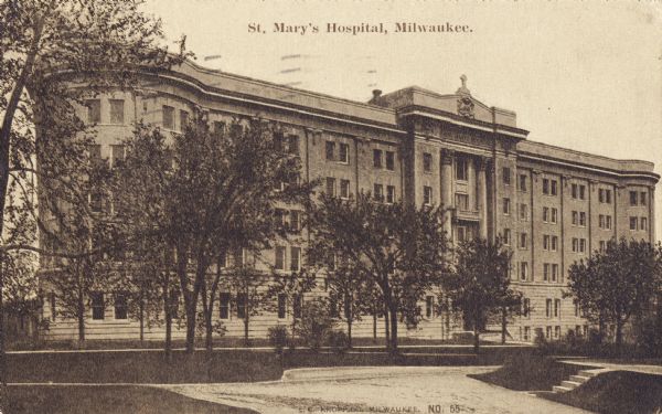 Exterior view of hospital with trees and paths in a large area  in front. Caption reads: "St. Mary's Hospital, Milwaukee."