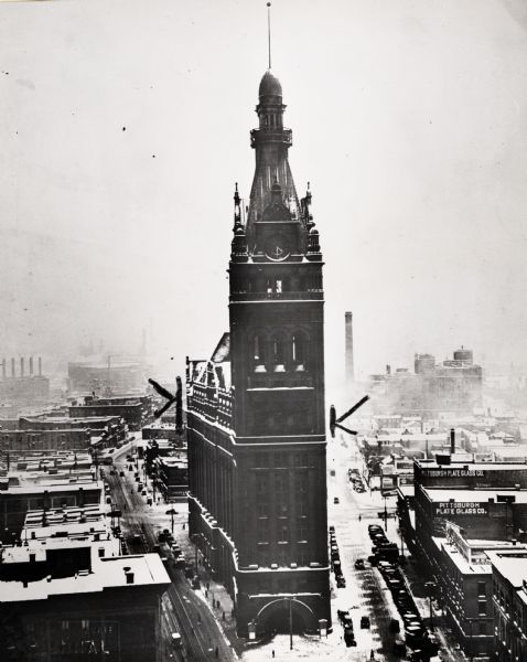 Elevated view of front of City Hall. Several buildings and streets surround City Hall, with cars on all the roads. Snow is on top of the buildings and the ground.