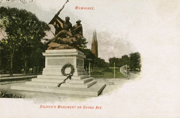 Soldier's Monument on Grand Avenue, with a wreath places at the base. Steeples of a church are in the background. Scroll work has been added to the upper and lower left sides. Caption at top reads: "Milwaukee." Caption at bottom reads: "Soldier's Monument on Grand Ave."
