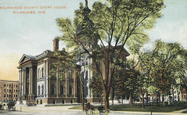 Color image of courthouse with a large tree and park on the left. View taken at an angle to the building from across the street. Horse-drawn carriages are on the road, and buildings are in the background to the left and right of the courthouse. Caption reads: "Milwaukee County Court House, Milwaukee, Wis."