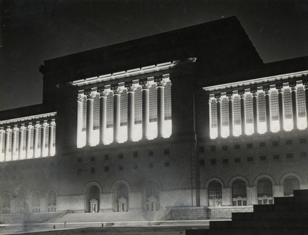 Nighttime view of the front center section of the courthouse. Strong interior lights highlight the fluted columns, while ground lights illuminate the entrances.