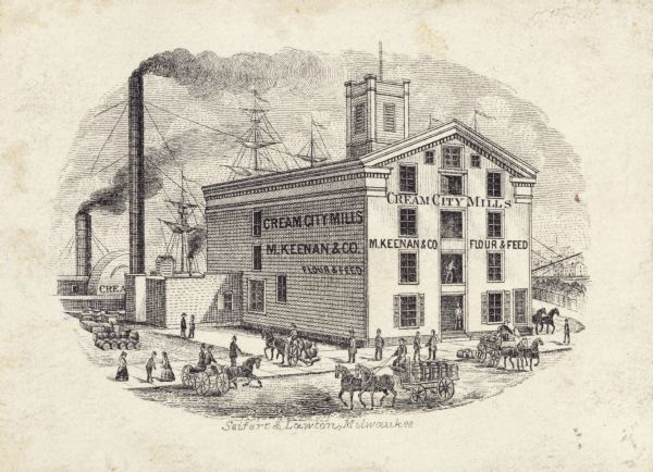 M. Keenan & Company, flour and feed mill.  Small print of mill on the water front.  River is behind the building with a steamboat and a ship.  A tall smokestack is to the left of the building. On the road in front and on the side are several horse-drawn carts and various people along the sidewalk.