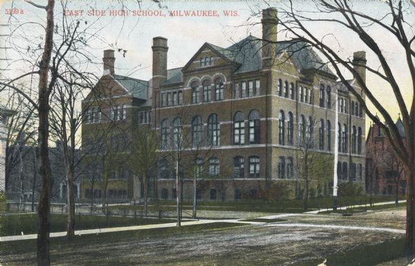 Exterior view across street toward the school on a street corner. The school building has five levels, with peaked roofs and several chimneys. A red building is in the right background. Caption reads: "East Side High School, Milwaukee, Wis."