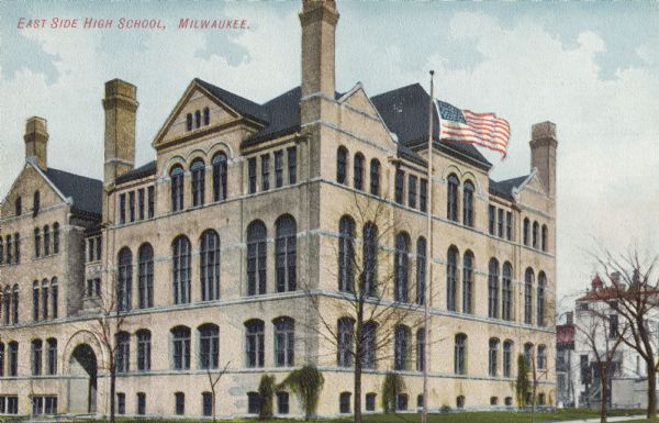 Exterior view of school. A flag on a flagpole is in the foreground. Caption reads: "East Side High School, Milwaukee."