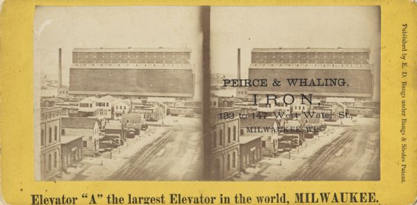 Stereograph; elevated view of what was supposedly the largest elevator in the world at the time.  Though there is a Peirce & Whaling Company imprint over the photograph, this company dealt in heavy hardware, railway supplies, etc., and the elevator does not necessarily belong to this company.  Elevator is in a large building in the background with several houses and businesses in the foreground.