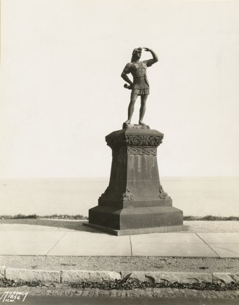 Statue located in Juneau Park. Figure has left hand to eyes looking to the right, with a horn in his right hand resting on his hip.  He stands on top of a plinth with Celtic designs and an inscription.
