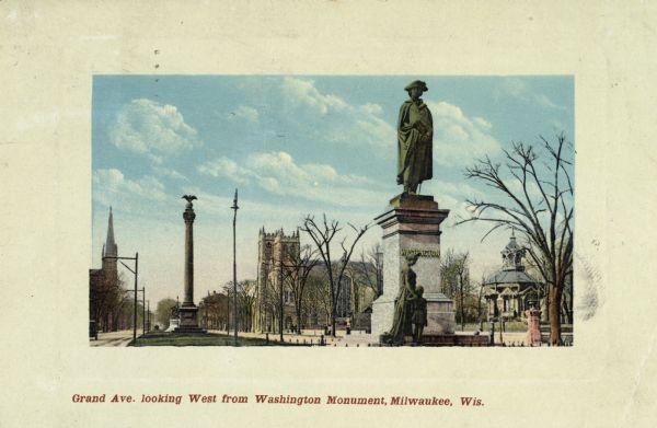 Looking west from Washington Monument. There is a monument on the right, with the view down the street on the left. A church, two other monuments, and several other buildings are in the background. Caption reads: "Grand Ave. looking West from Washington Monument, Milwaukee, Wis."