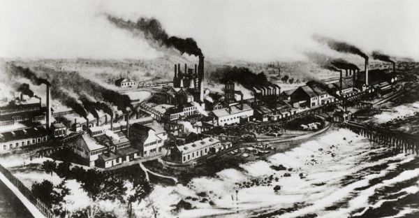 Milwaukee works. Long steel mill located on the bank of either a lake or a river. Multitudes of smokestacks, tracks, and small buildings.