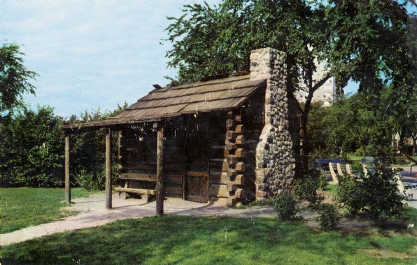 View toward the front entrance of the cabin with a stone chimney on the right.