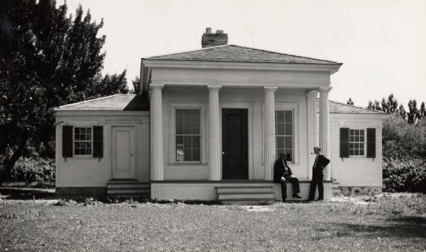 House built by Benjamin Church in 1844.  Restored, it stands in Estabrook Park.  Two men near front porch, from left to right: Frederic Heath, President of the Milwaukee County Historical Society, and H. Harshaw Hay, architect.