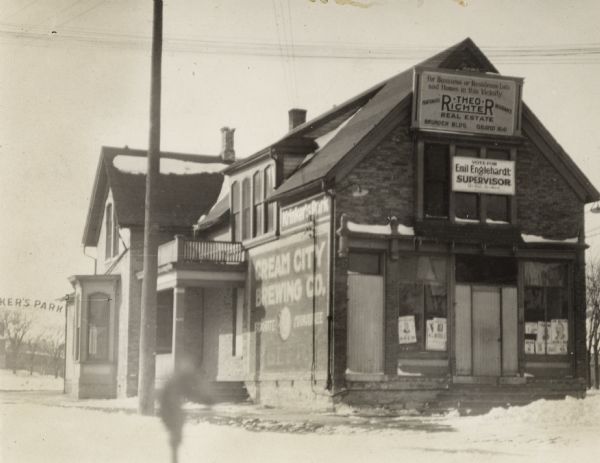 Building at corner of Lisbon Avenue and North Avenue.  A manuscript note on the reverse of the photograph calls this Neumueller's Park, which may have been either a local name for it, or the official name at some other period of its history.  This building, which is covered with signs and billboards, was destroyed before 1924 to make room for a filling station.  A spot check of city directories from 1890 to 1924 do not list this as an official public park.  Arched sign with portion of park name is on the left of the building.