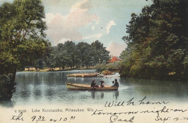 A boat with five people are on a lake surrounded by trees. Behind them are several docked boats. In the background is a park area with a red-roofed building. Caption reads: "Lake Kosciuszko, Milwaukee, Wis."