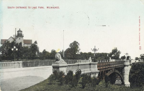 South entrance to park. The bridge has stone lion sculptures on each of its corners, as well as ornate street lamps. A lighthouse and attached buildings are on the left behind the trees. Caption reads: "South Entrance to Lake Park, Milwaukee."