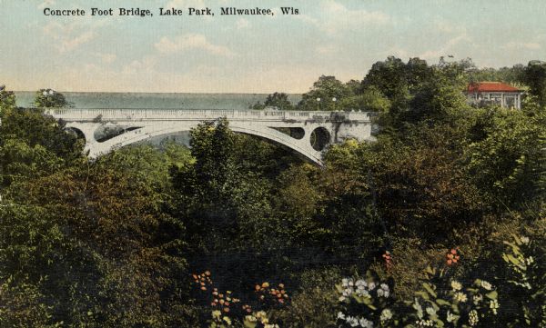 Elevated view over trees and bushes toward the footbridge. A building with a red roof is on the far right. Beyond the bridge is Lake Michigan. Caption reads: "Concrete Foot Bridge, Lake Park, Milwaukee, Wis."