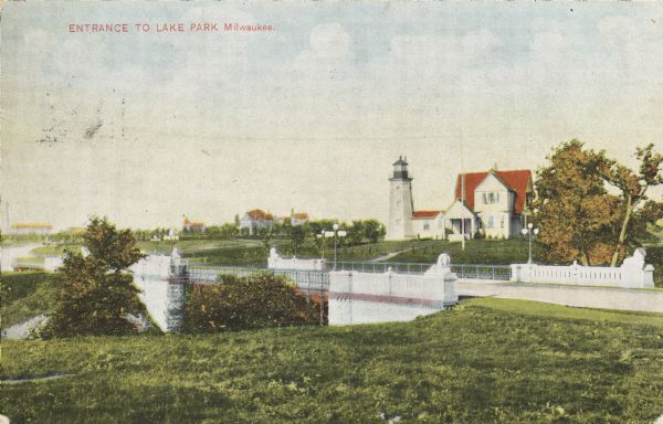 View across lawn toward the bridge on the right. The lighthouse is in the background, as well as several other buildings in the distance. The bridge is flanked by stone lions on each corner. Caption reads: "Entrance to Lake Park, Milwaukee."