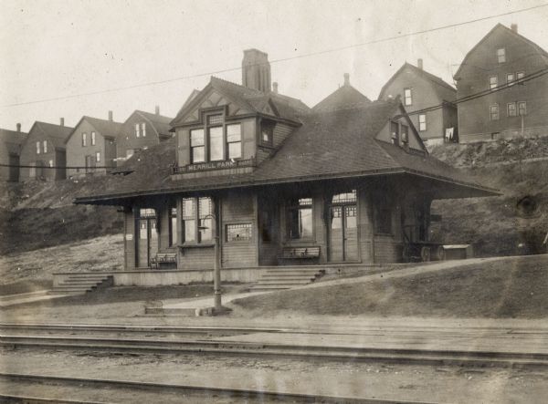 Part of the Chicago, Milwaukee, & St. Paul Railway. Small station, at the bottom of a hill. Behind the station on top of the hill is a line of houses.