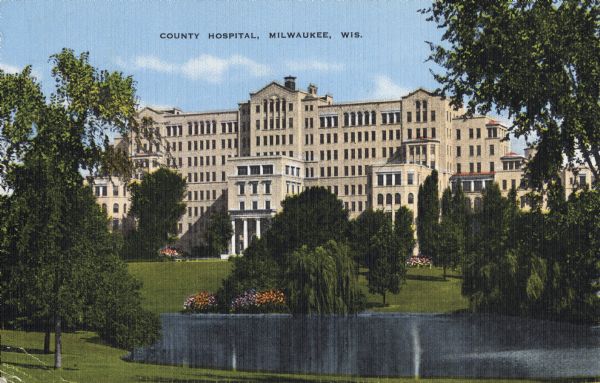 The hospital entrance is behind a small pond that is surrounded by trees and a landscaped lawn. Caption reads: "County Hospital, Milwaukee, Wis."