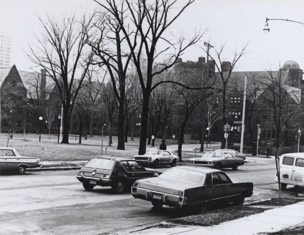Left to right: Holton, Merrill, and Johnson Halls. Cars are parked along the road, including a Ford Gremlin and Chevrolet Camaro, in the lower part of the image.