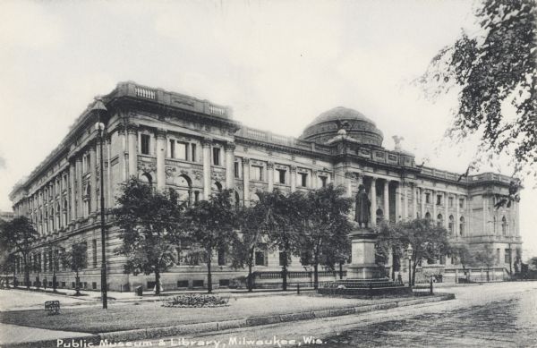 Front facade of library building from across the street behind a median strip, which has a statue and a sign that reads "Keep Off the Grass". Caption reads: "Public Library and Museum, Milwaukee, Wis."