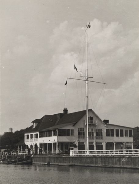 Exterior view of the club. A mast with flags stands outside of the club on the pier.
