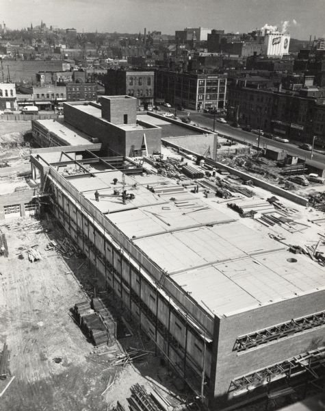 Elevated view of construction of the new building, at Sixth Street and Highland Avenue. The downtown can be seen in the background, including the Schlitz company in the upper right.