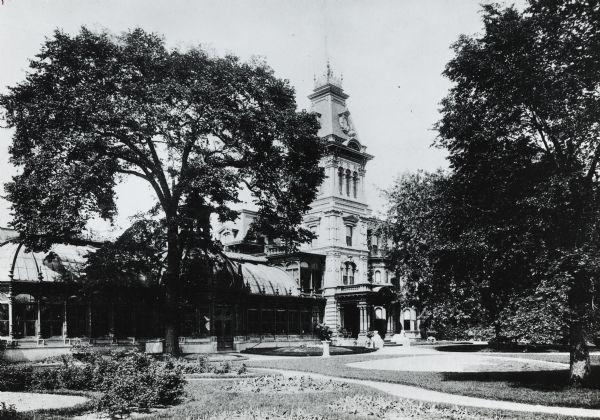 Ninth Street and Grand Avenue.  House sits behind trees and a lawn.  The main house is in the center, and a greenhouse, with a domes roof, branches off the house to the left.