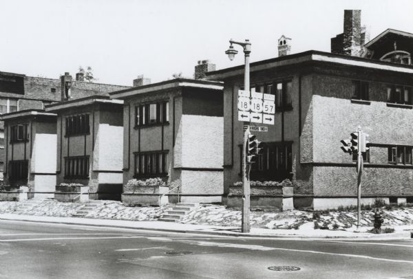 View from street of American System houses, four identical buildings in a row, designed by Frank Lloyd Wright, located at 1102-112 North 27th Street. They were demolished in 1974. A road sign for state routes stands at the street corner.