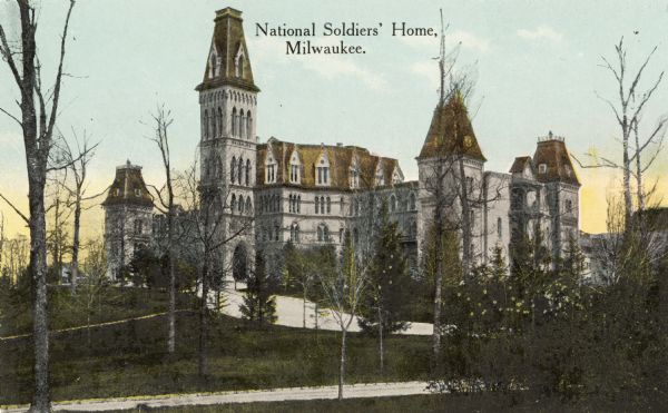 Looking southwest. The facility has since become part of the U.S. Veterans Administration Center at 5000 West National Avenue. Two paths and trees surround the building. Additional buildings are in the background. Caption reads: "National Soldiers' Home, Milwaukee."
