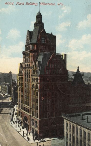 Elevated view of the building, with main arched entrance on the left.  There is a bridge on the left over the river. Caption reads: "Pabst Building, Milwaukee, Wis."